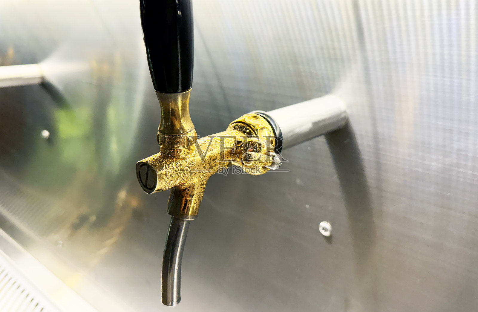 特写黄铜啤酒龙头正在出酒。照片摄影图片