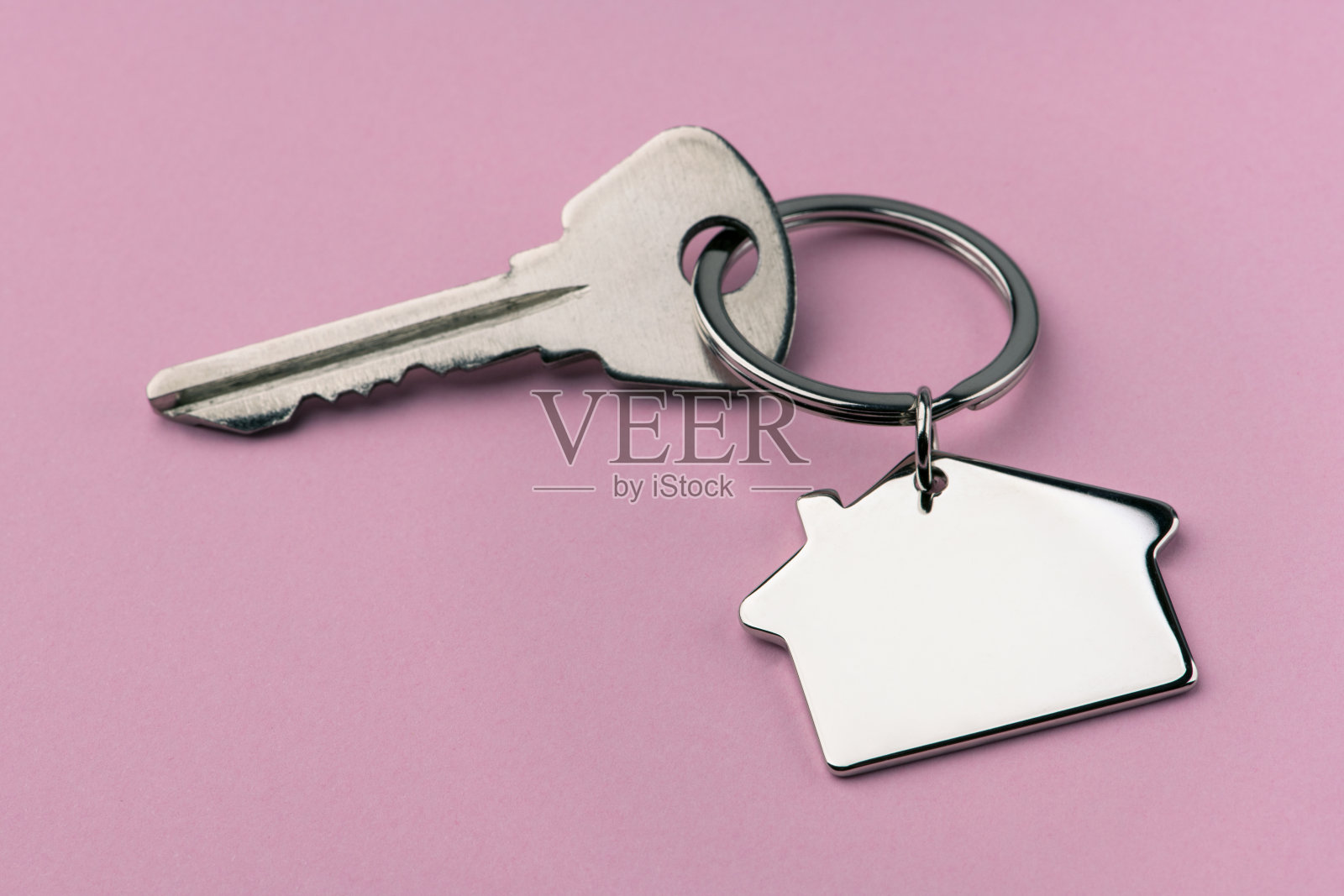 粉色背景上的房屋钥匙照片摄影图片