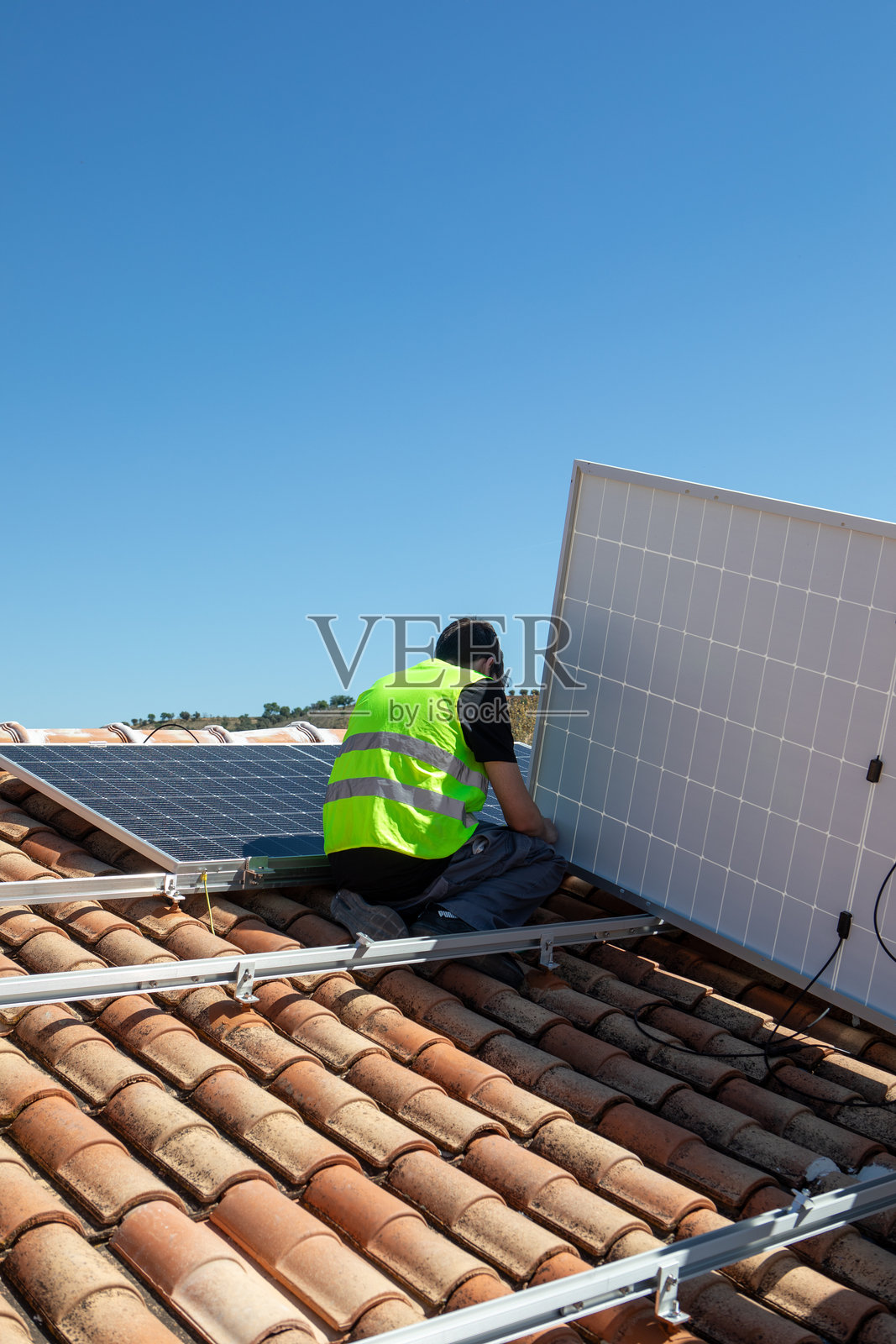 午后晴朗蓝天下，住宅屋顶上的太阳能电池板安装照片摄影图片