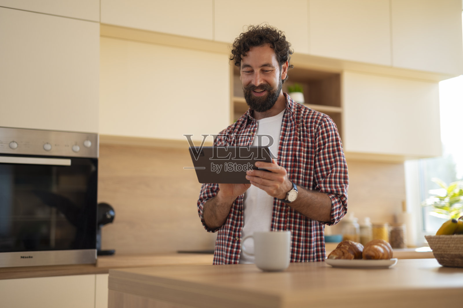 男人在厨房吃早餐时使用数码平板电脑照片摄影图片