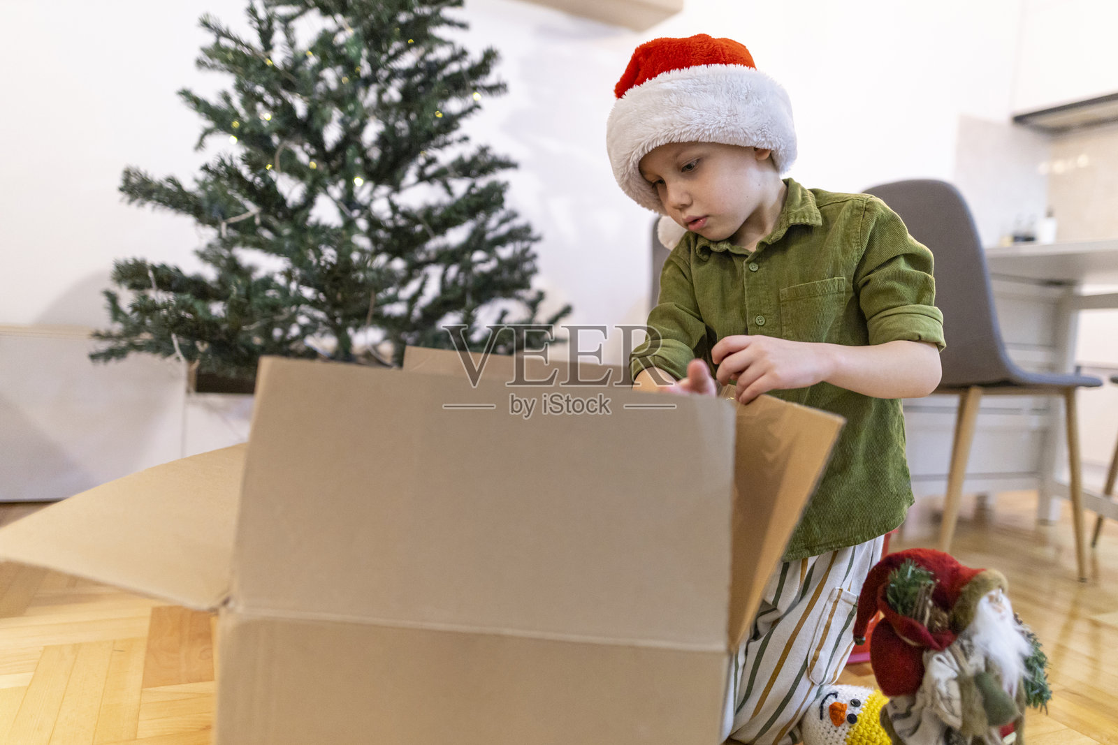 男孩戴着圣诞帽，从储物箱里拿出圣诞装饰品。照片摄影图片