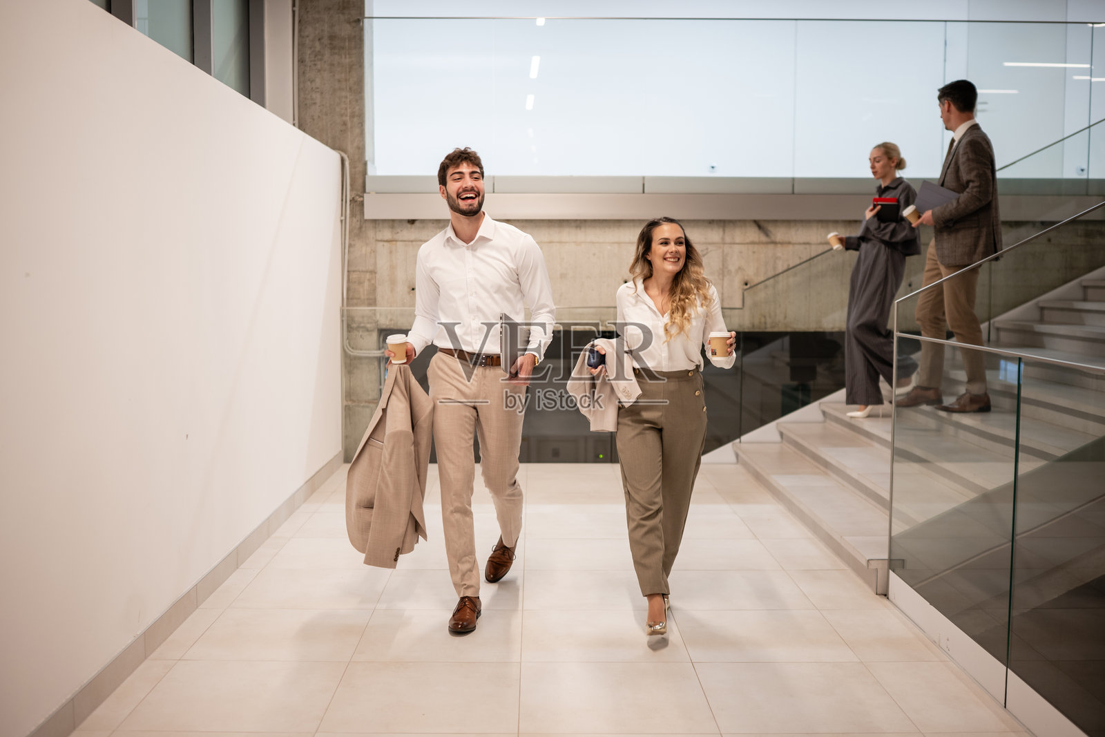 同事们在公司走廊里行走，面带微笑交谈。照片摄影图片