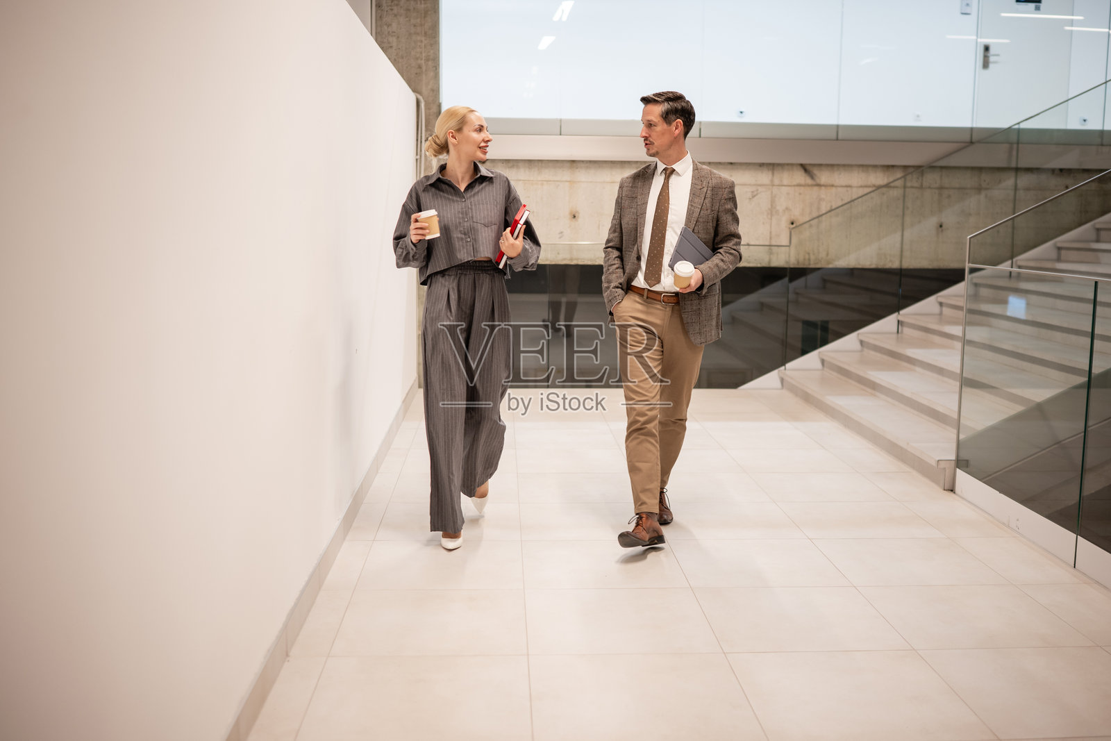 商务同事在现代办公楼里边走边谈照片摄影图片
