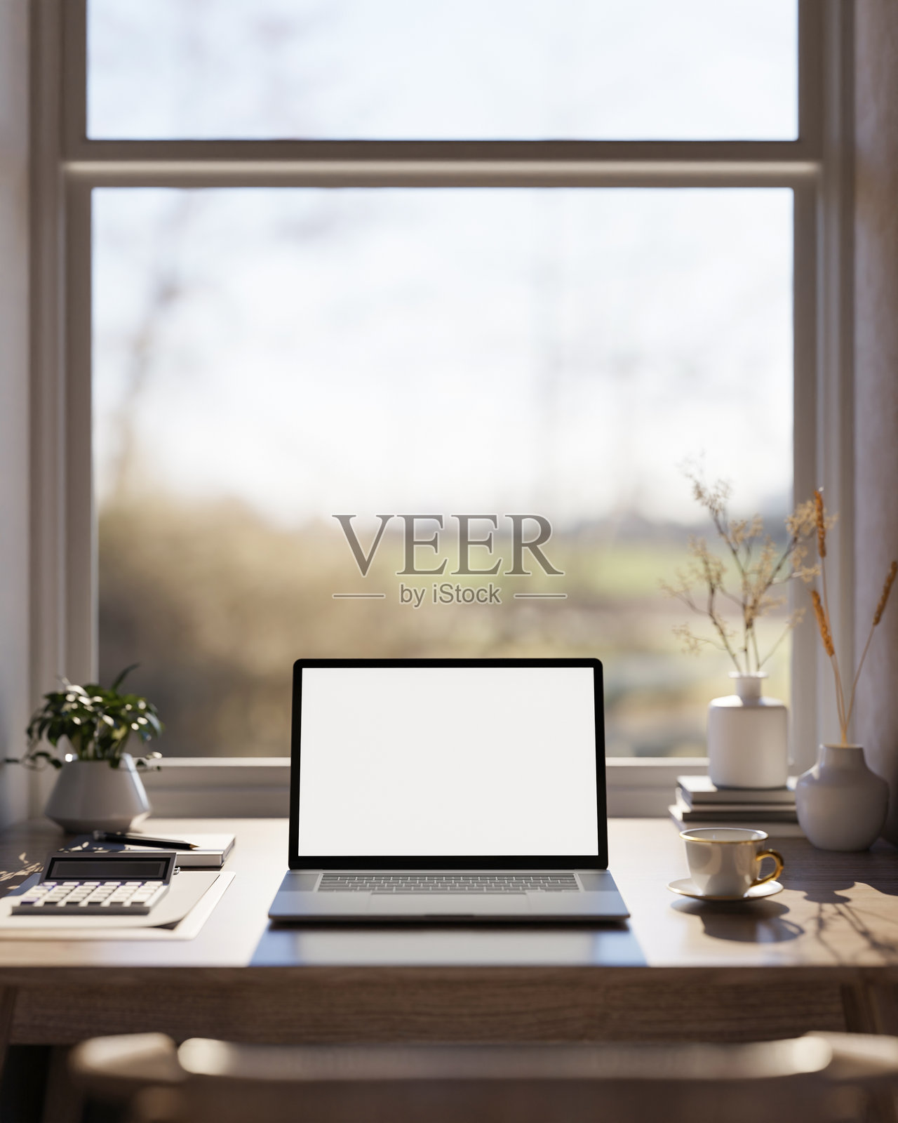 温暖阳光透过窗户洒在木桌上，桌上放着一台白色屏幕的笔记本电脑、计算器和咖啡杯。照片摄影图片