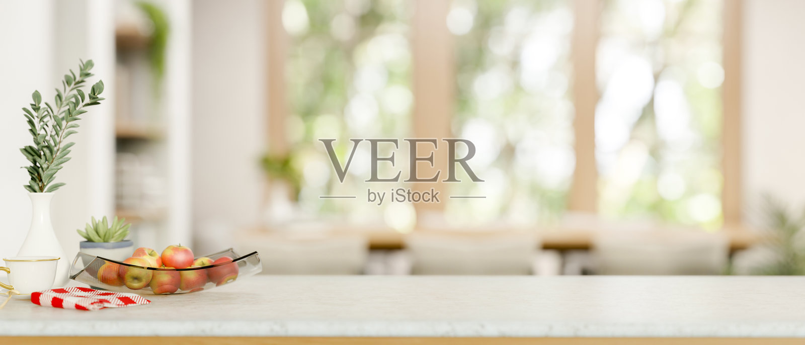 花园景观厨房的大理石料理台上，盘子里的苹果，旁边放着杯子、抹布和花瓶。照片摄影图片