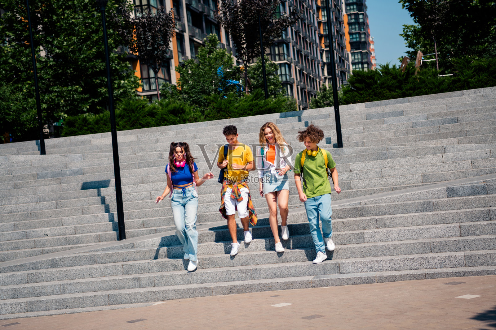 一群来自不同背景的青少年在阳光明媚的城市中享受户外休闲时光，周围环绕着现代建筑。照片摄影图片