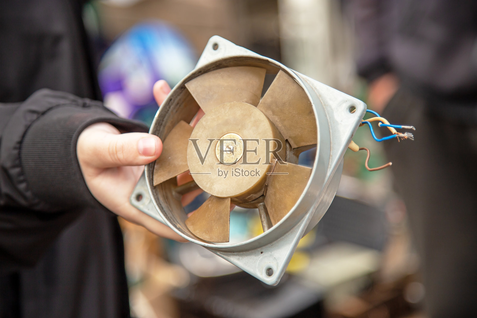 手中拿着一个金属风扇，露出电线的旧式工业冷却器照片摄影图片