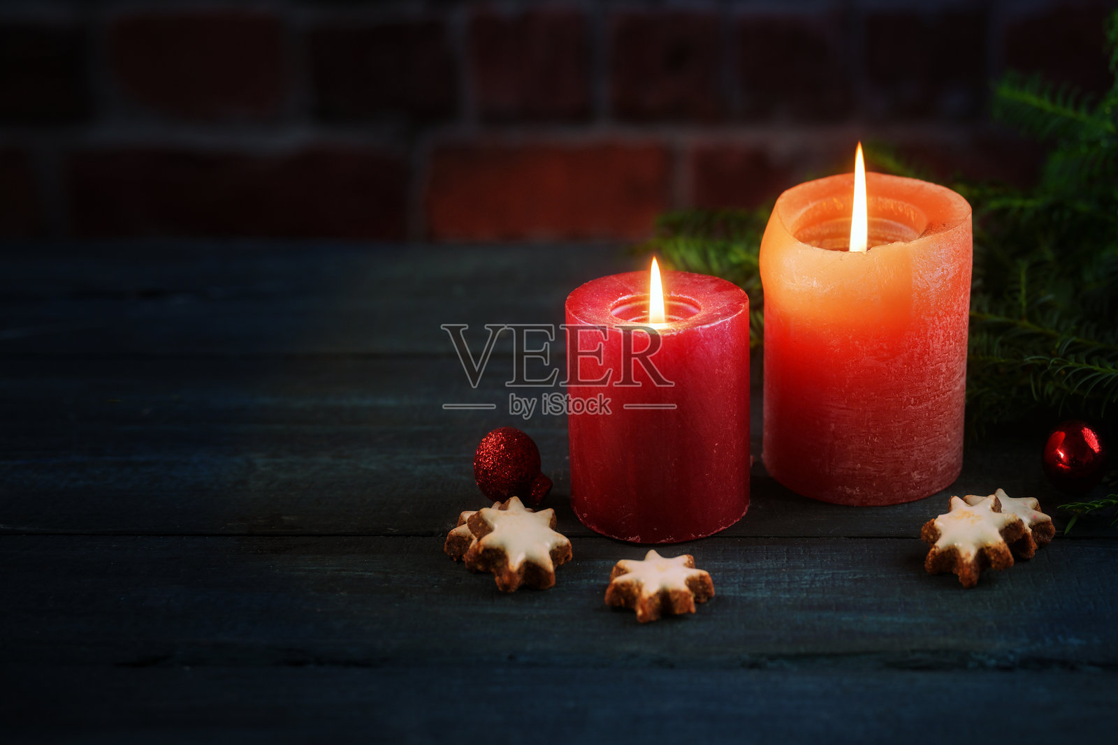 两支红色蜡烛、饼干、装饰球和松枝，背景为深色砖墙，适用于圣诞节、降临节或新年的贺卡，有大量复制空间，精选柔焦，浅景深照片摄影图片