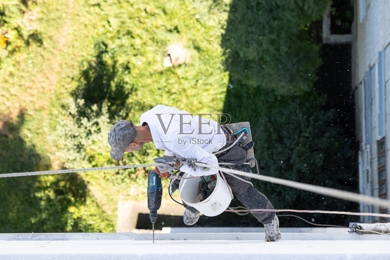 建筑工人使用钻头固定聚苯乙烯板，用于建筑外墙保温。照片摄影图片