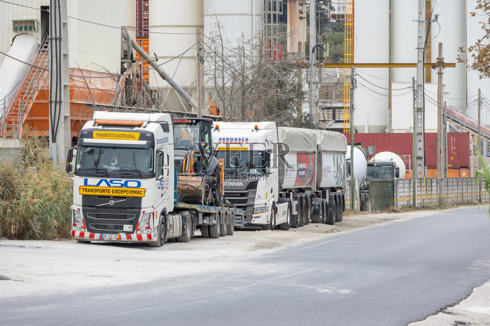 停放着重型运输卡车和水泥筒仓的工业区照片摄影图片