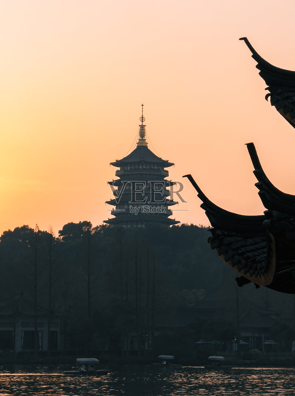 杭州西湖日落景色，湖中有宝塔和小船照片摄影图片
