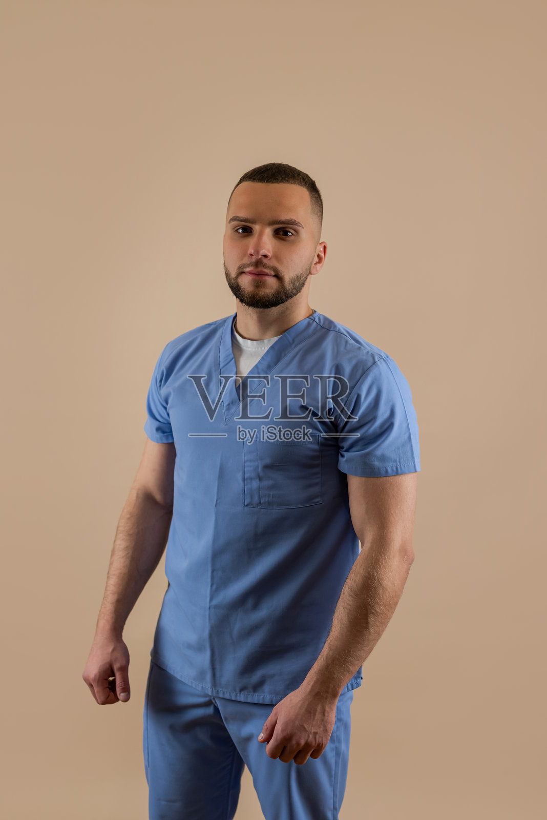 身穿蓝色制服的年轻高加索男性医生肖像，室内拍摄照片摄影图片