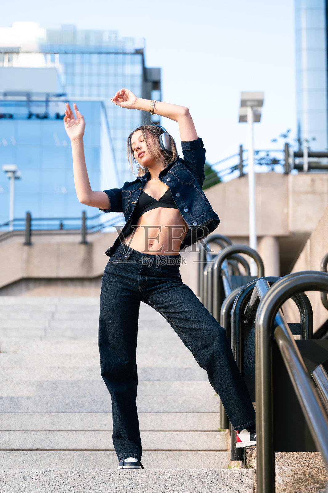 戴着耳机在城市阶梯上跳舞的女人照片摄影图片