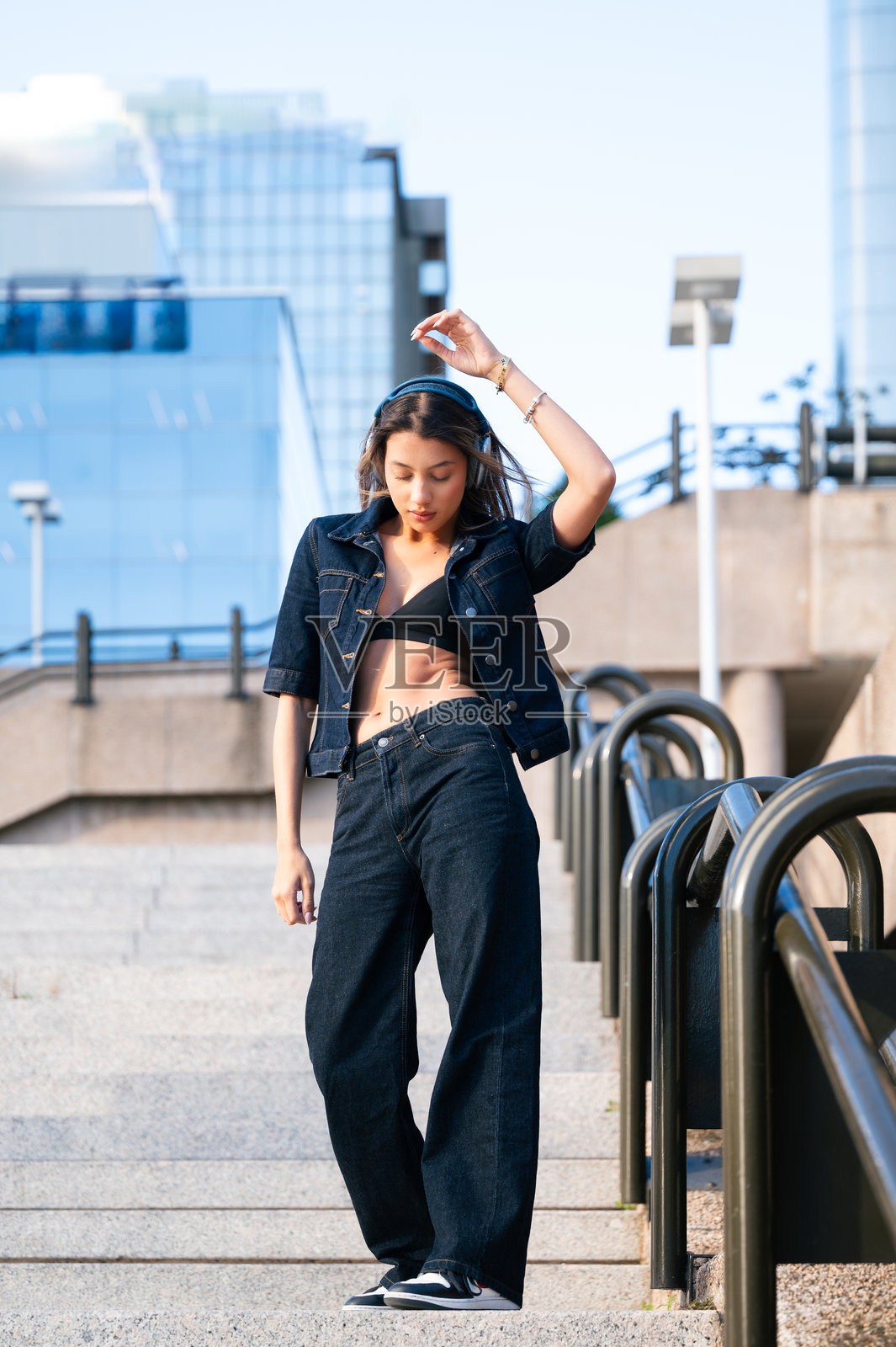 女子戴着耳机听音乐，在城市生活中跳舞照片摄影图片