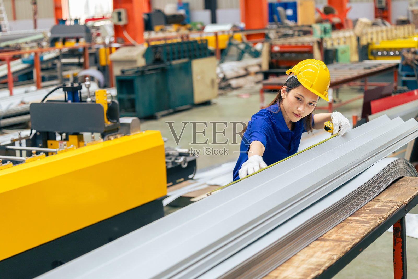 年轻的亚洲女工程师在金属板材厂测量产品尺寸，进行专业工作照片摄影图片