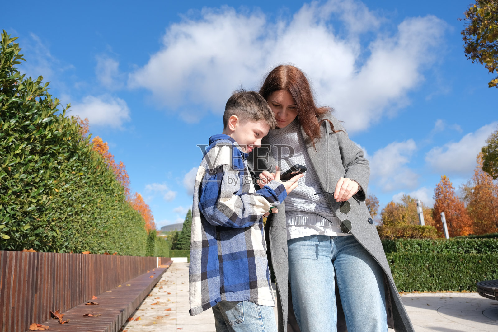 母子俩在街上试戴新太阳镜，并用手机拍照照片摄影图片