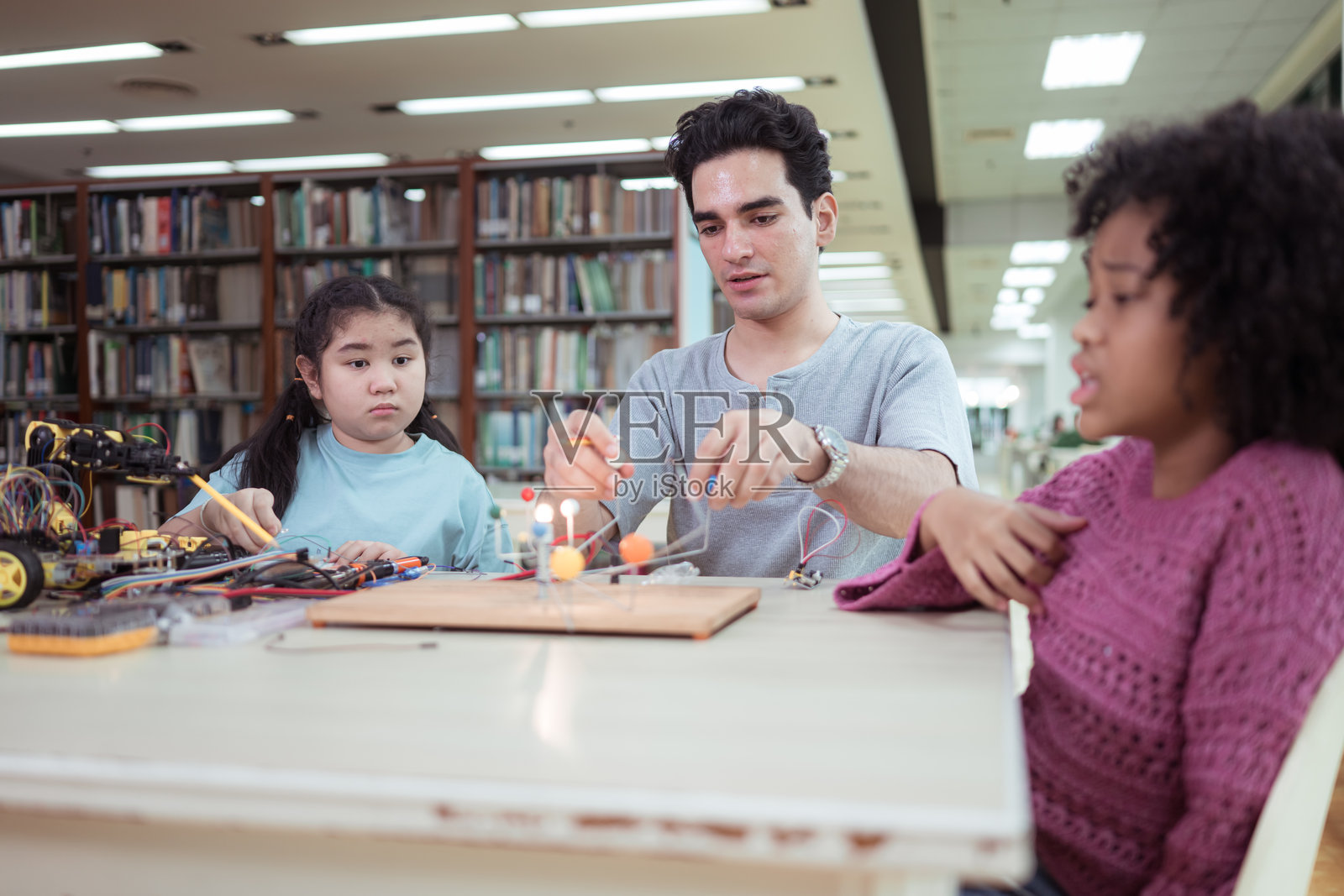 STEM课程上，一位老师在图书馆指导学生进行机器人项目照片摄影图片