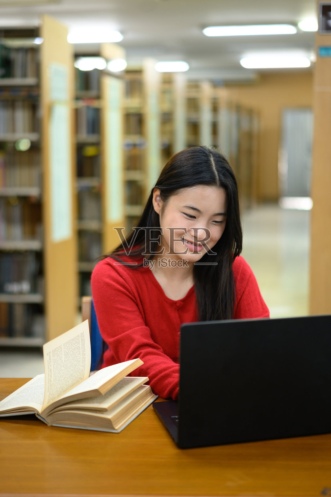 少女教育概念。她在图书馆使用笔记本电脑。照片摄影图片