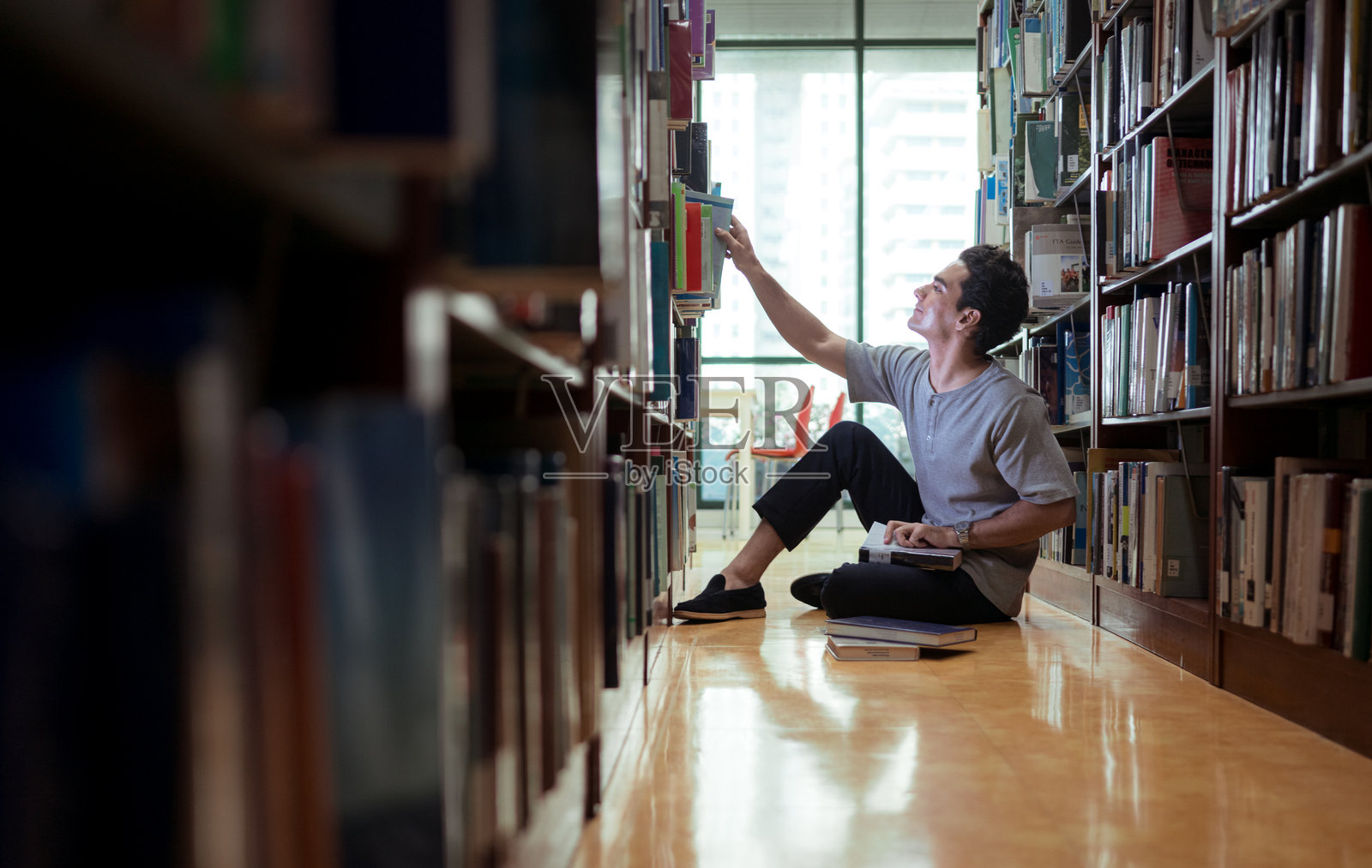一个年轻人坐在图书馆地板上，专心致志地阅读书籍照片摄影图片