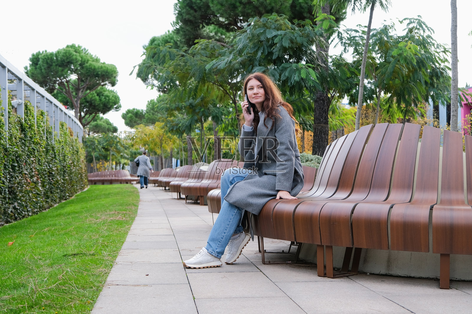 美丽的女子坐在城市公园的长椅上使用智能手机照片摄影图片