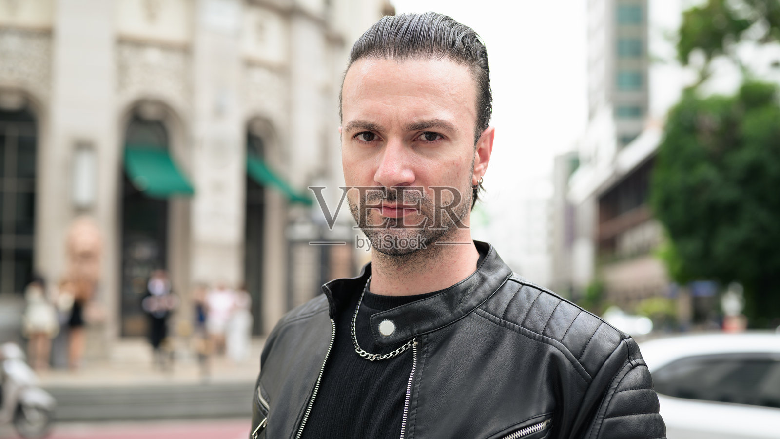穿着黑色皮夹克的英俊胡须男士在城市街道上摆姿势照片摄影图片