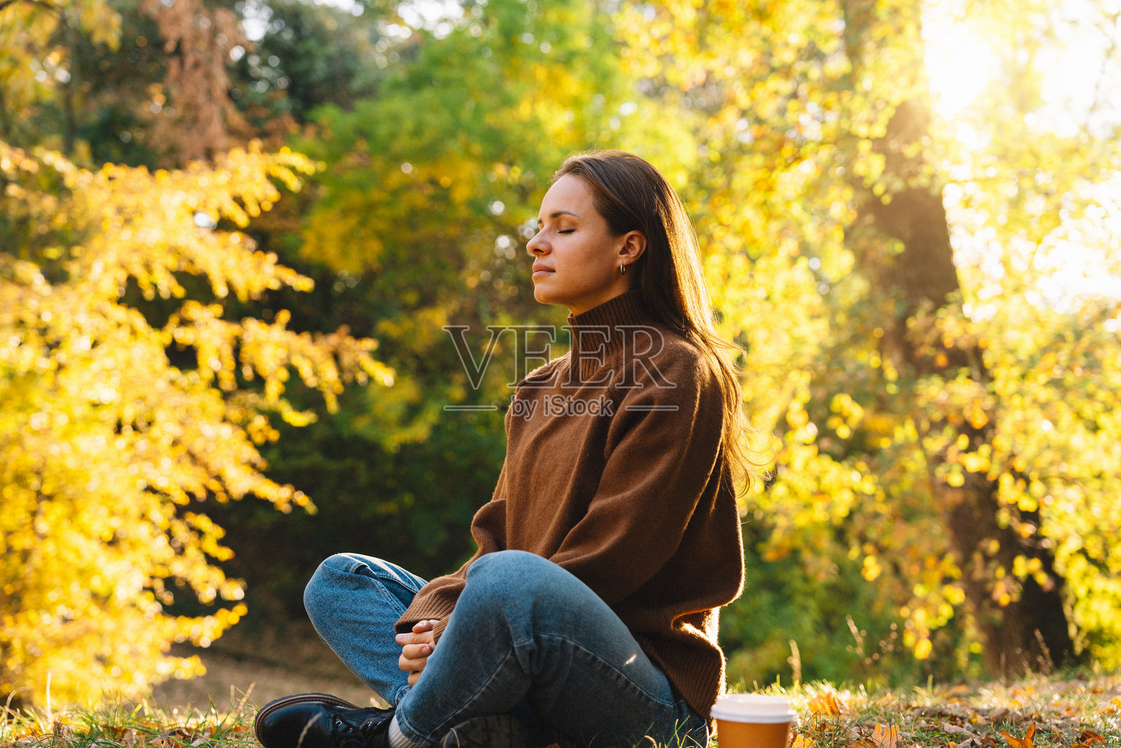 秋季自然公园里，一位宁静的女性在冥想，重拾与自然的联结。照片摄影图片