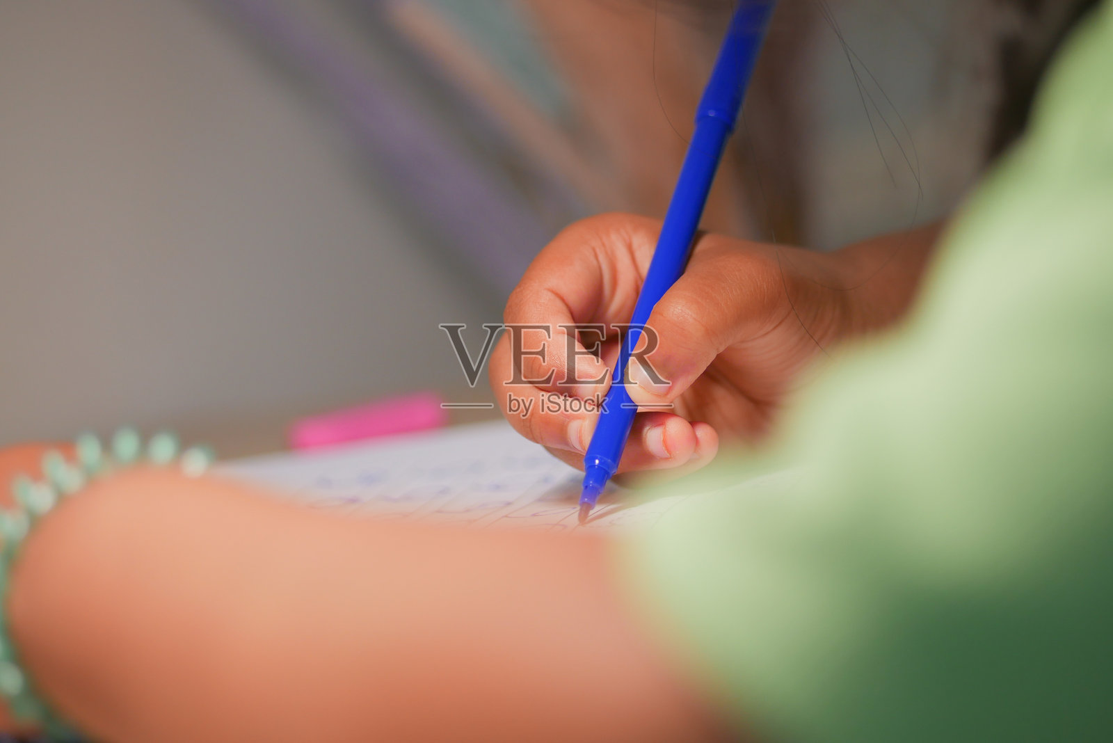 孩子在学习时间于书桌前用蓝笔书写照片摄影图片