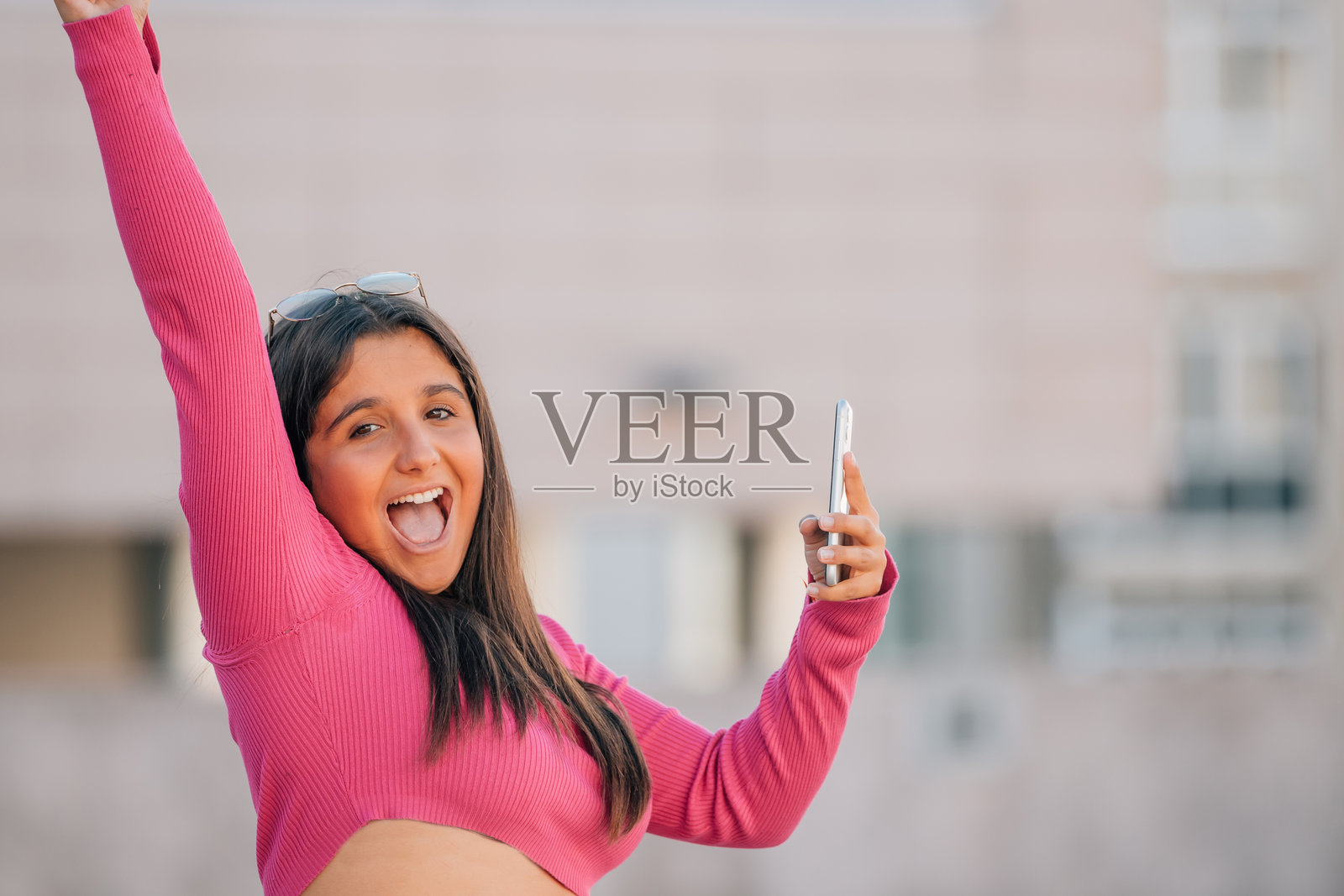 女孩在街上拿着手机，喜悦地尖叫照片摄影图片