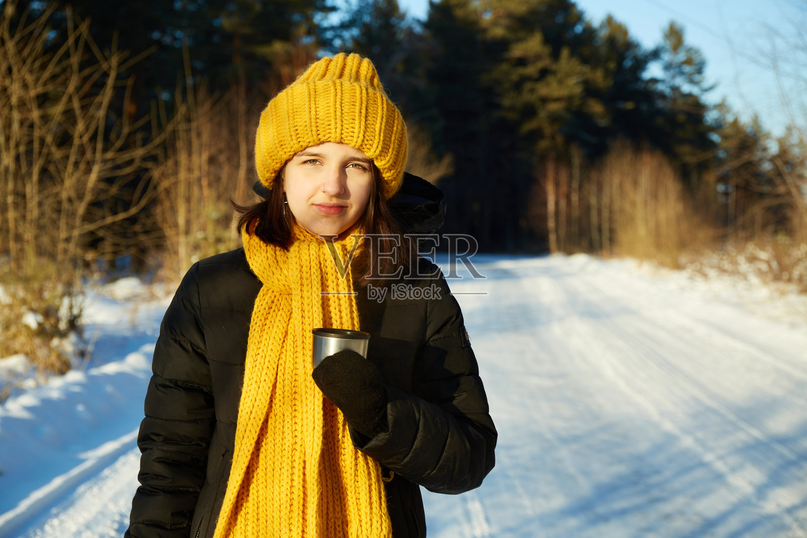寒冷冬日，女孩在户外捧着一杯热茶，享受周末时光。照片摄影图片