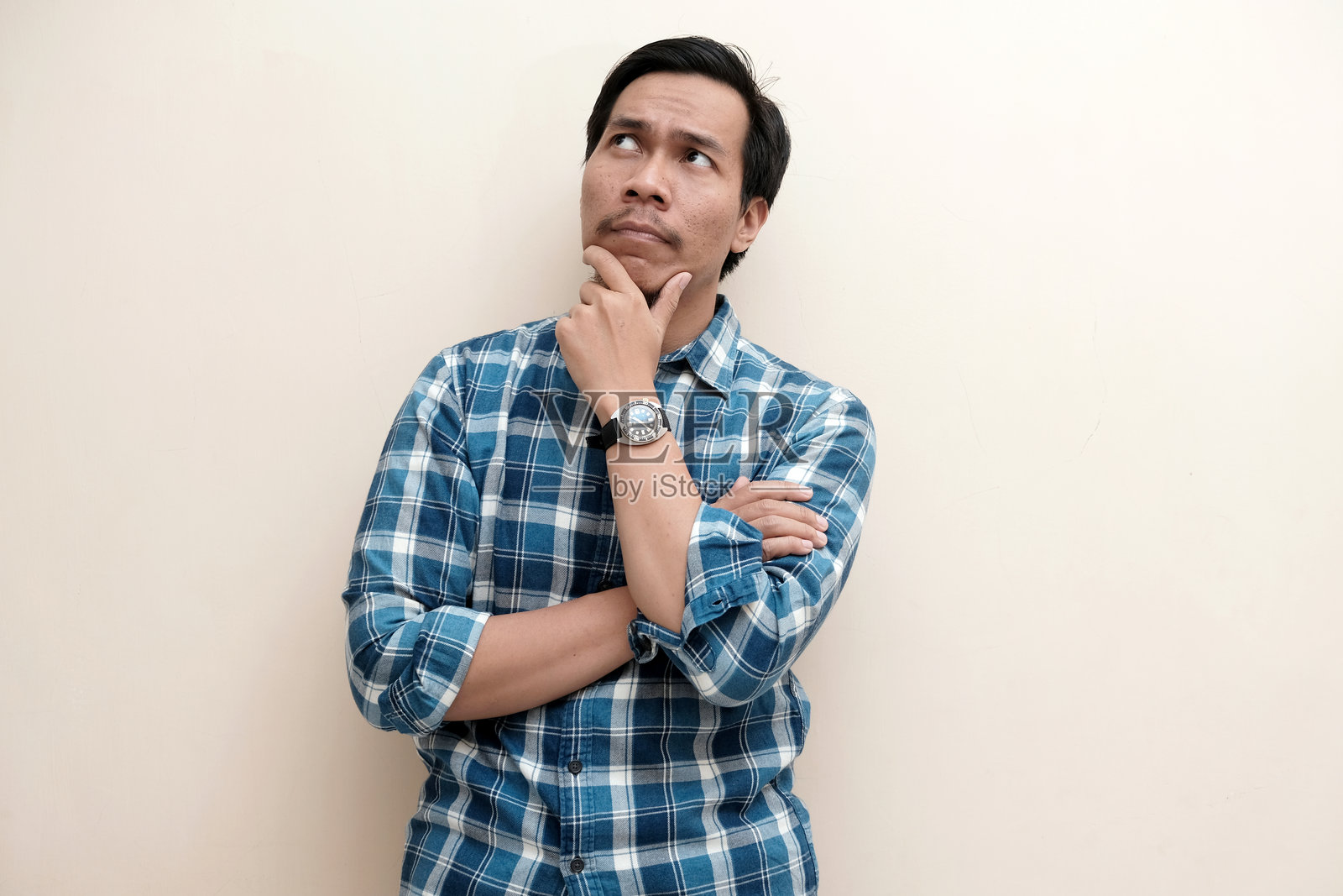 一位东南亚男子穿着法兰绒衬衫，看向右上角，若有所思照片摄影图片