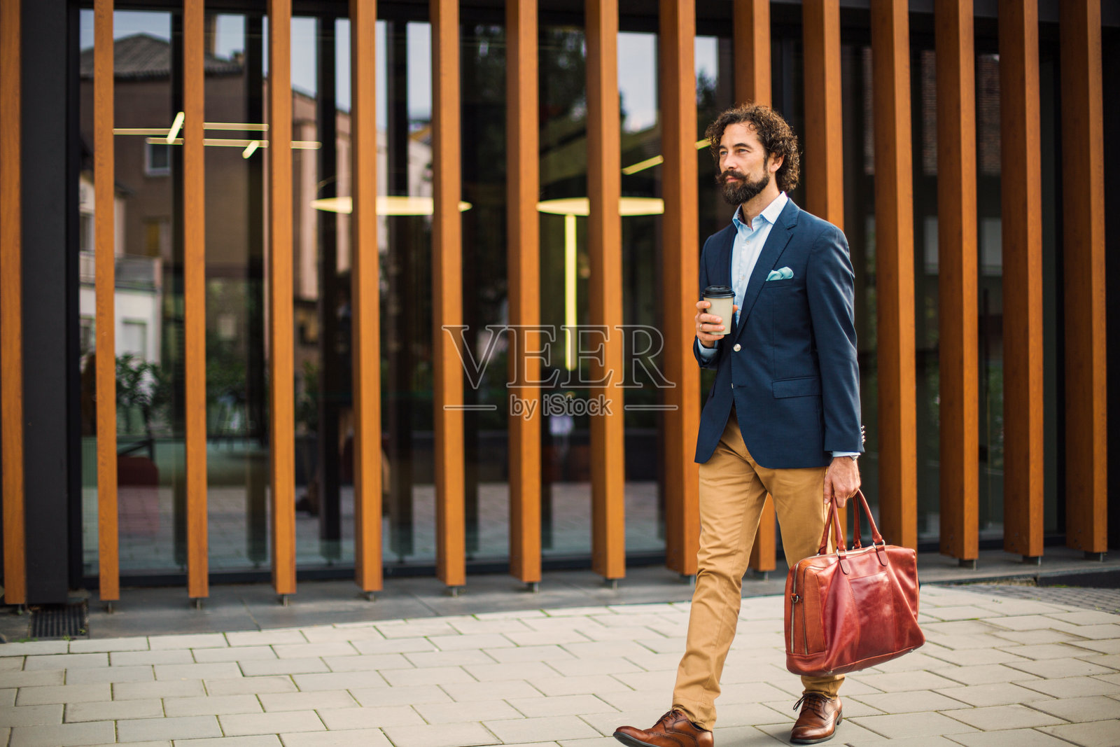 商务人士在城市中行走，手持咖啡和公文包照片摄影图片
