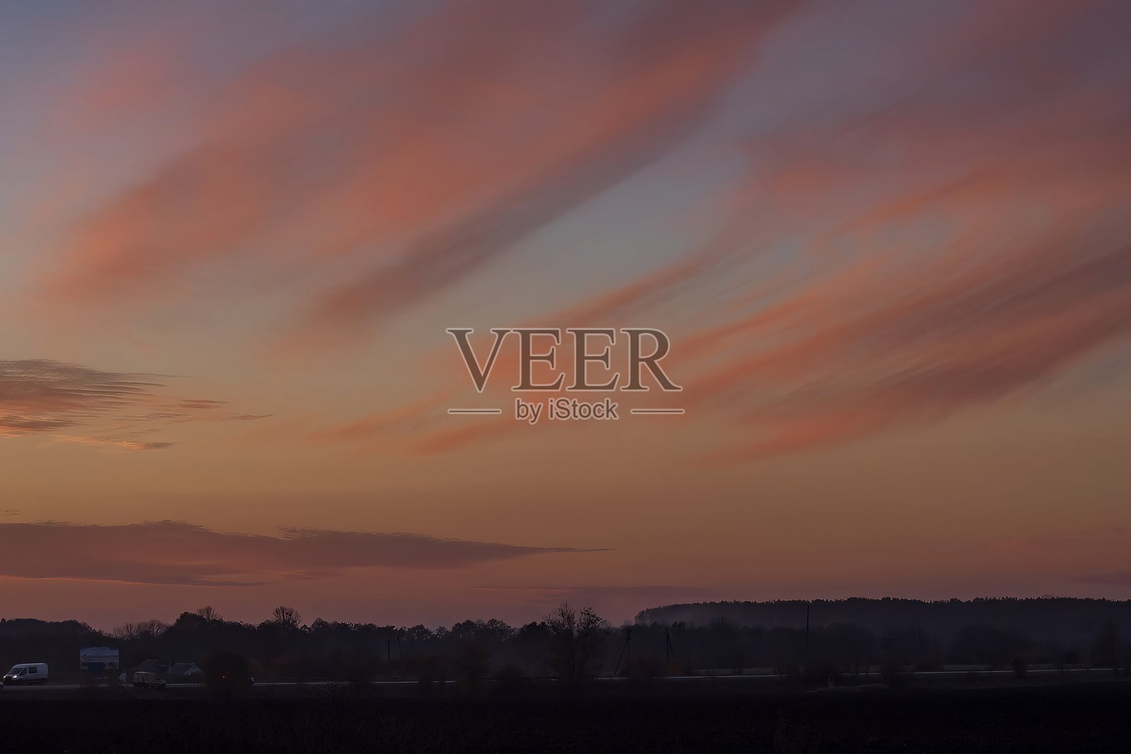 夕阳下的天空色彩鲜艳，橙色和粉色的云彩被落日照亮。照片摄影图片