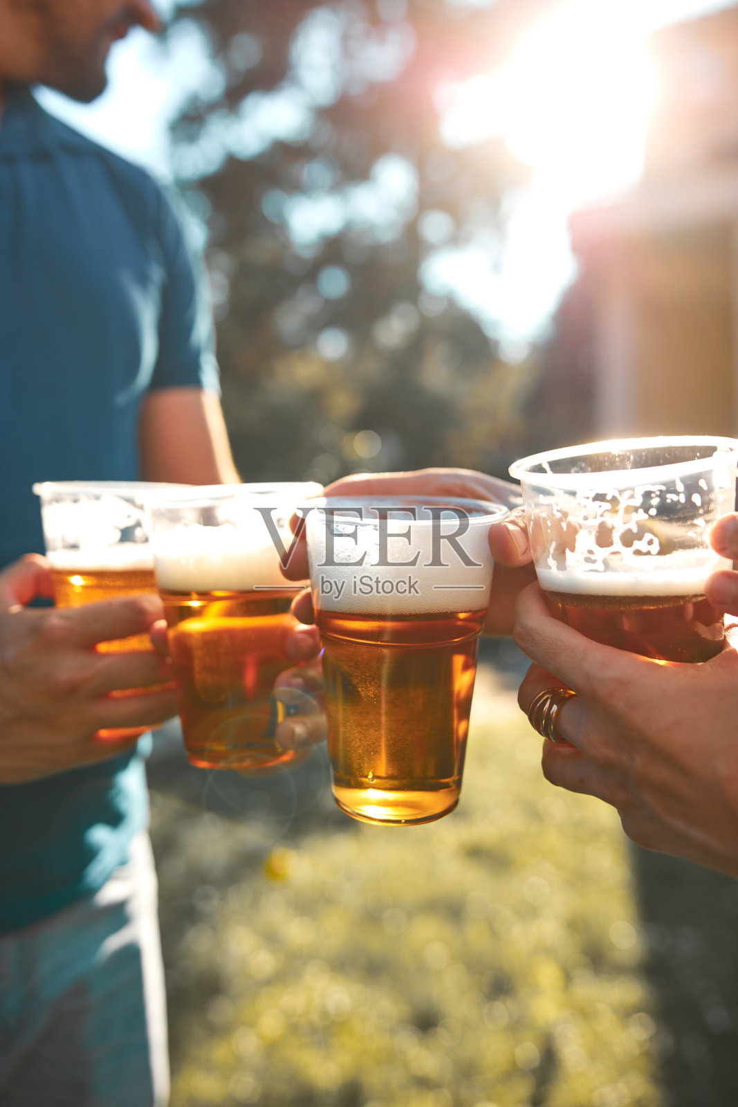 人们在户外举着啤酒杯，享受夏日时光。照片摄影图片