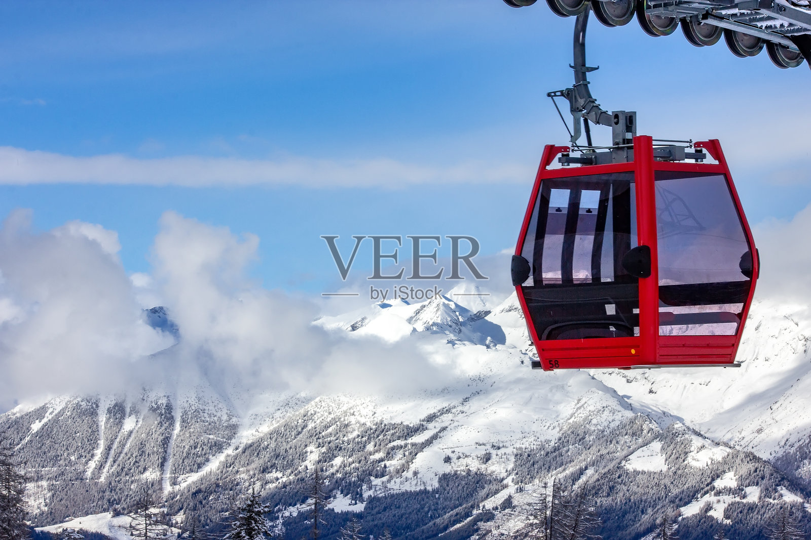 红色的贡多拉缆车正缓缓爬升，驶向白雪皑皑的奥地利山峦。照片摄影图片