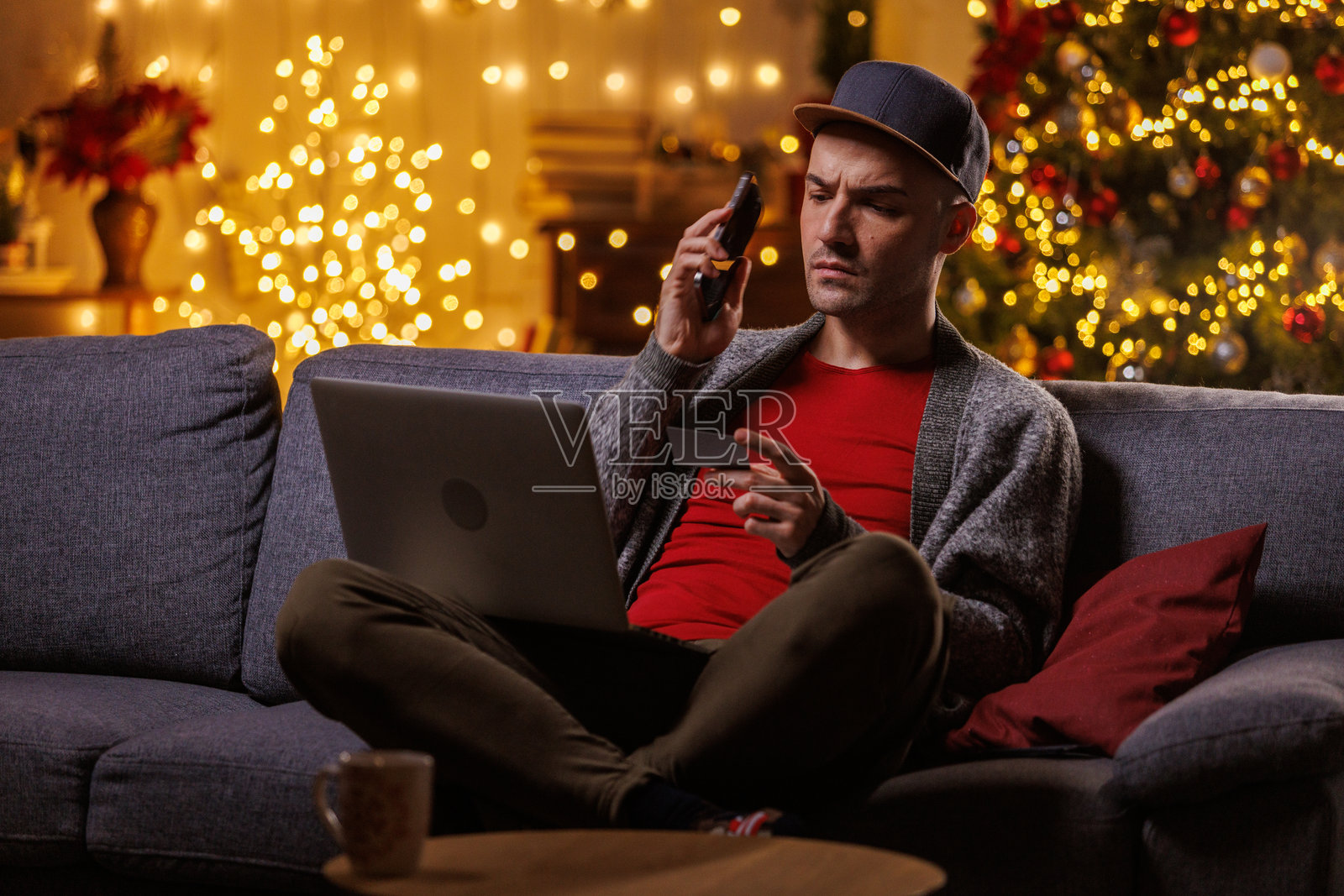 圣诞节，男人在家中放松，身边放着笔记本电脑和手机，营造温馨的节日氛围。照片摄影图片