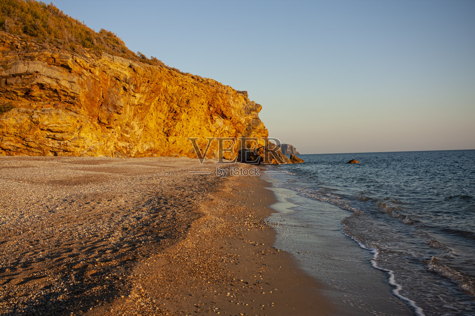 夏日美丽的海边落日，阳光照耀在岩石上。照片摄影图片