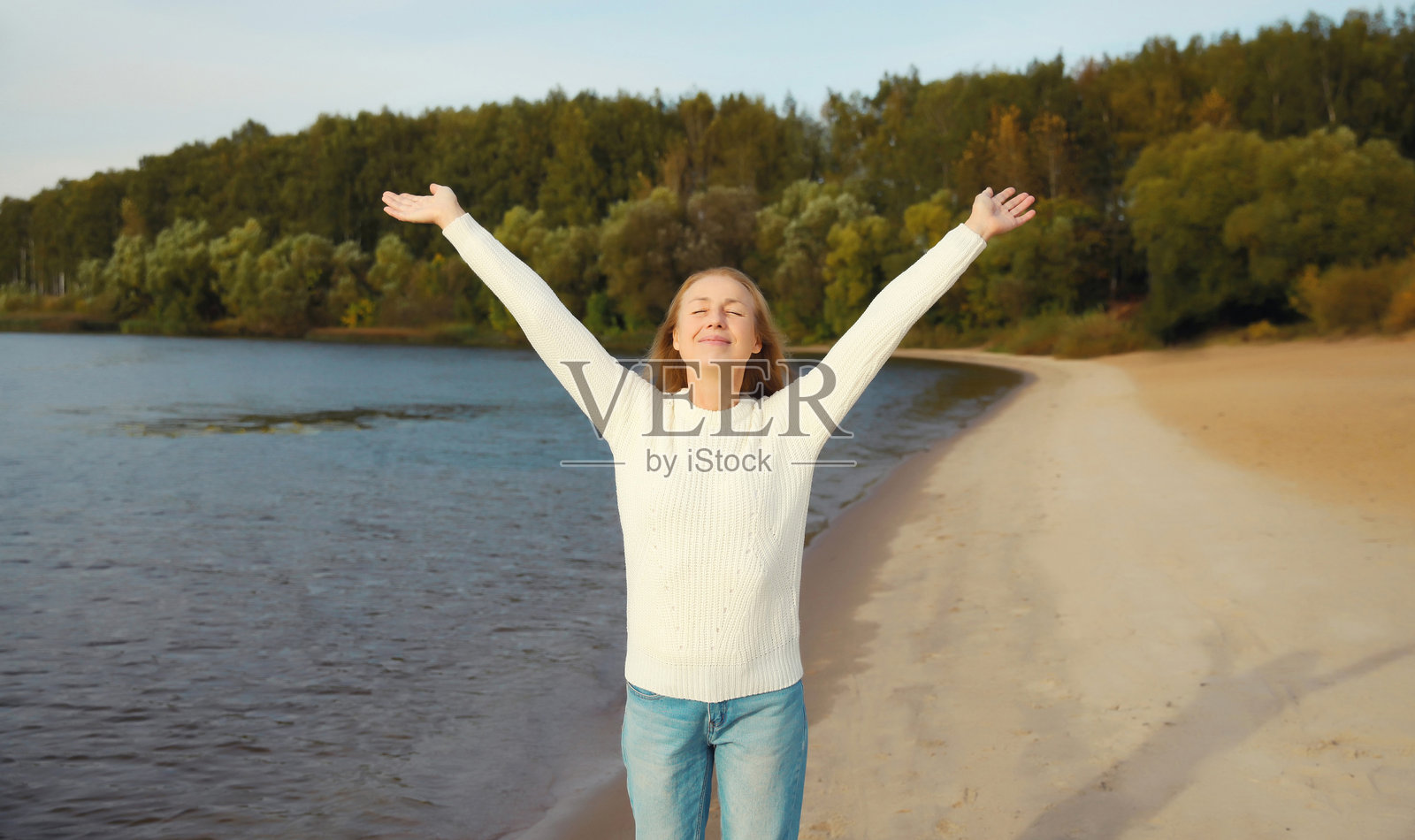 一位快乐微笑的女士在海滩上，享受着风景，天气温暖，她正站在海岸边。照片摄影图片