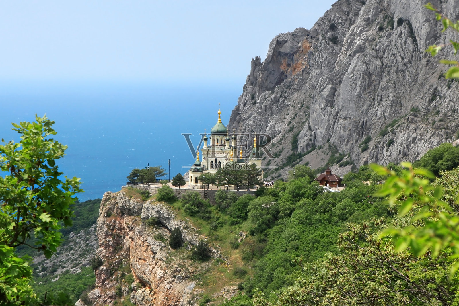俯瞰风景：岩石峭壁上的东正教教堂，俯瞰海岸，周围环绕着郁郁葱葱的绿色森林和山脉照片摄影图片