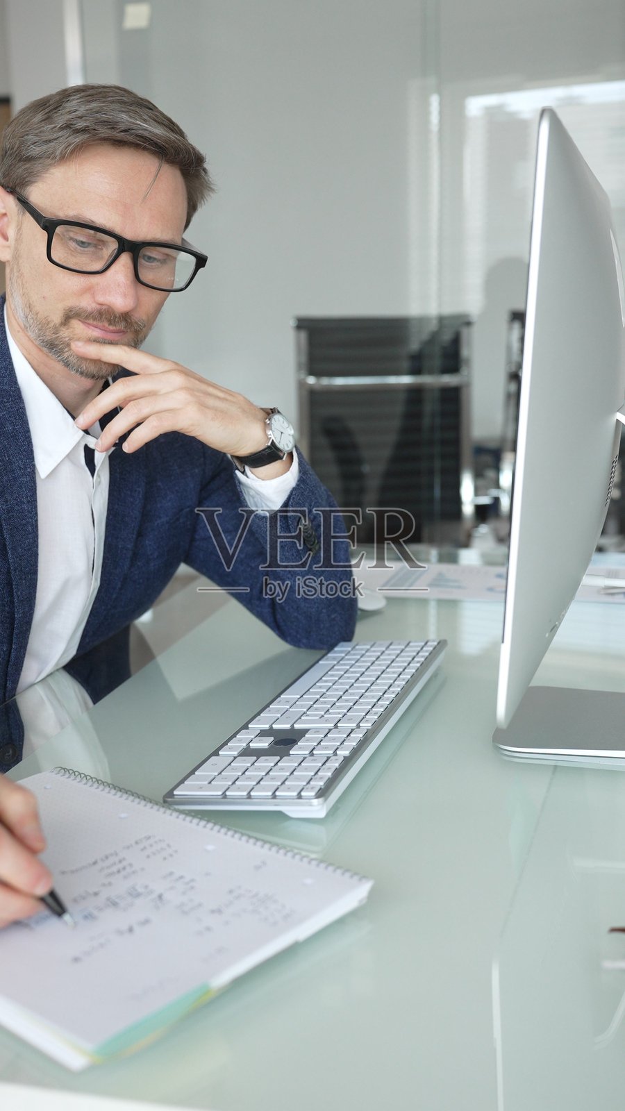 穿着蓝色夹克的专业商务人士在现代办公室的台式电脑上工作，专注于工作和业务任务。商务人士概念照片摄影图片