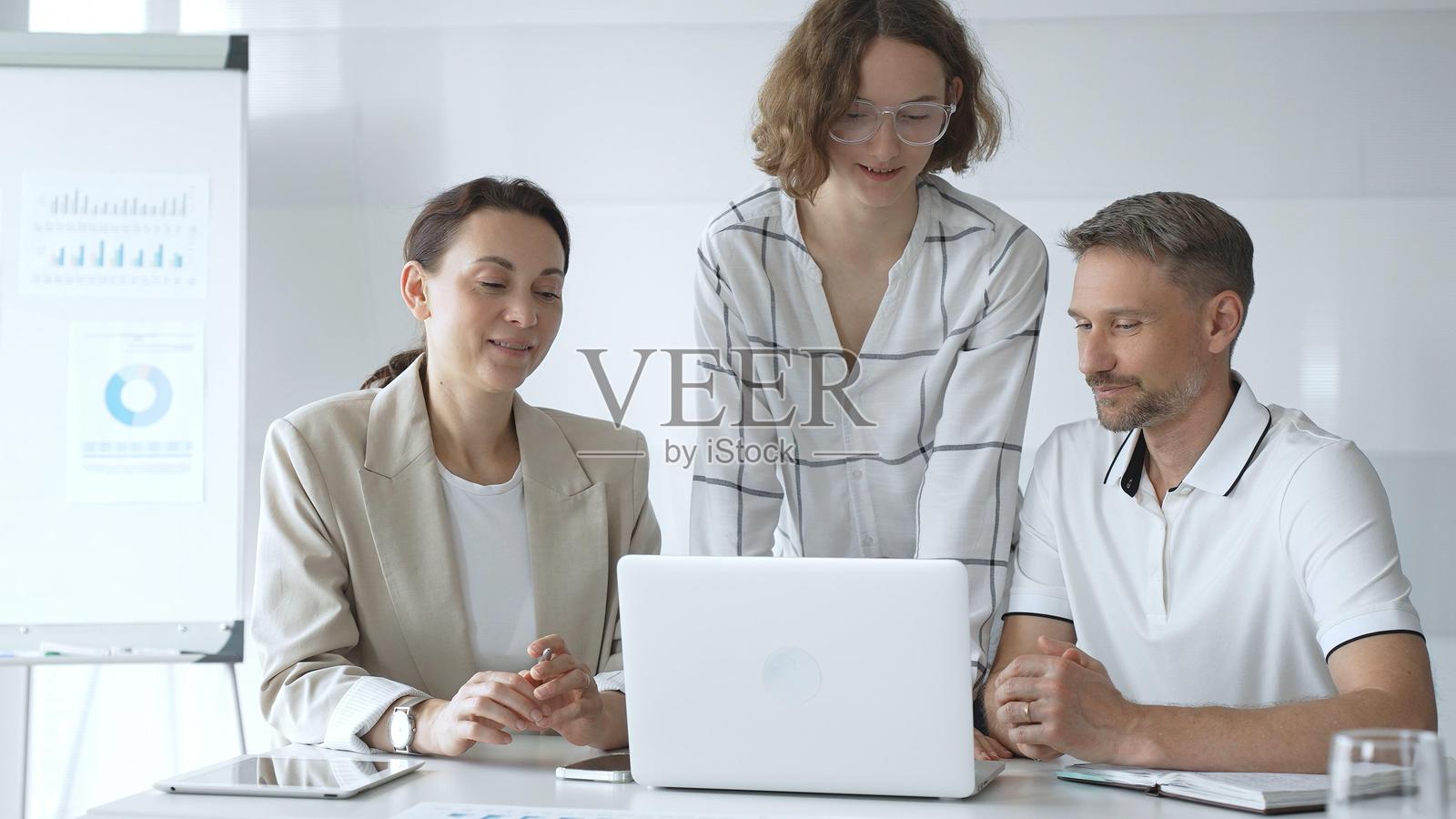 在现代办公室里，商务人士团队在富有成效的会议中协作，并在笔记本电脑上分析数据，以促进团队合作和战略决策。照片摄影图片