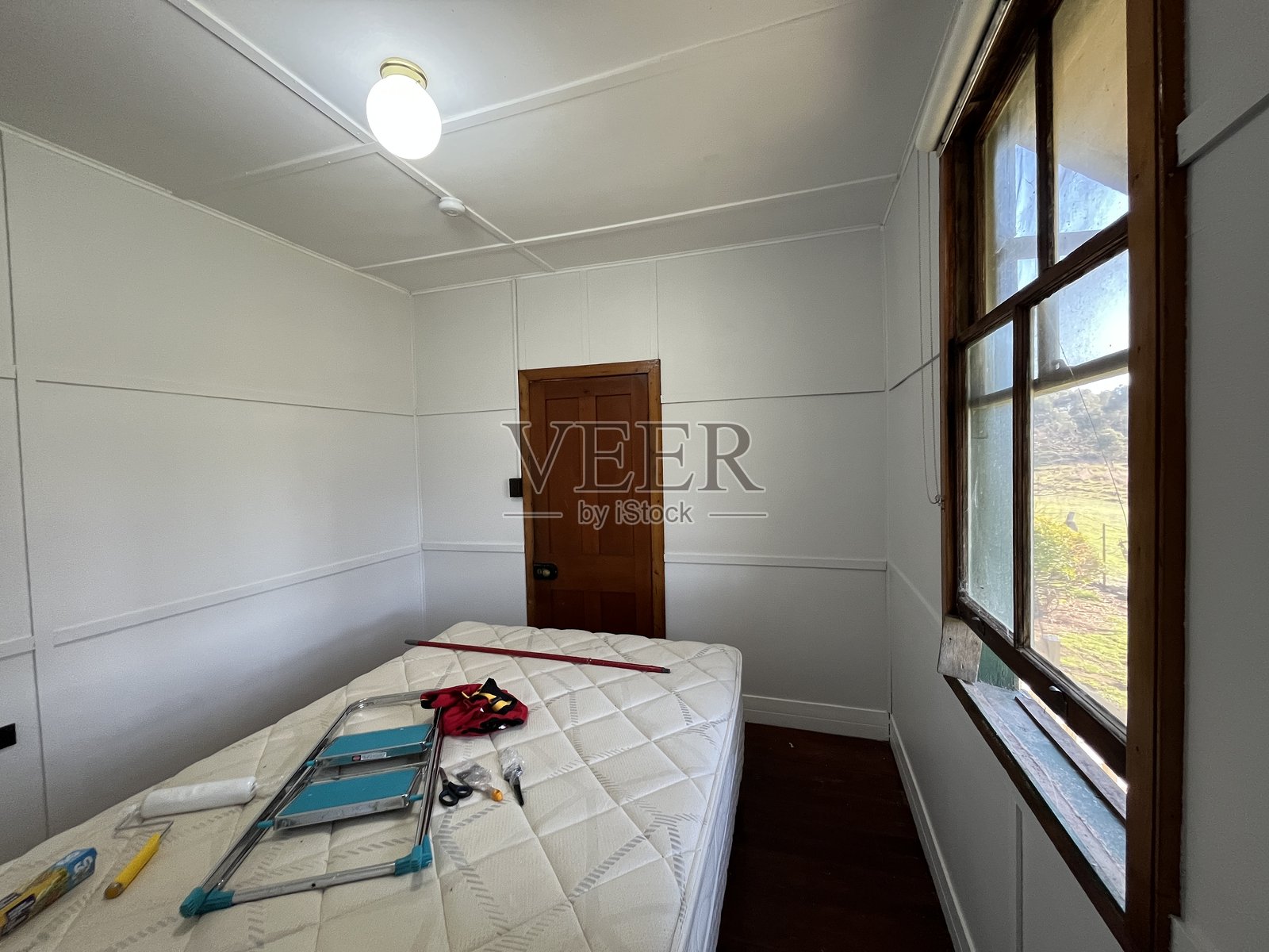 翻新中的老乡村房间，深色木墙正在被粉刷成浅灰色。照片摄影图片