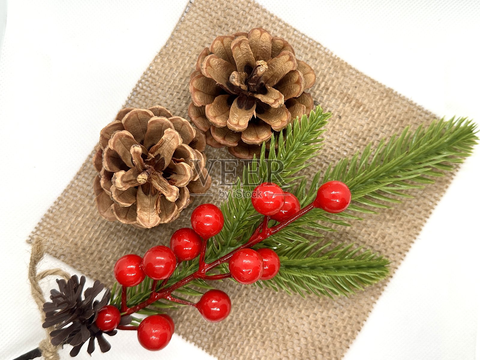松果和浆果枝的节日花束，置于天然织物上，适合假日和冬季装饰及手工制作照片摄影图片