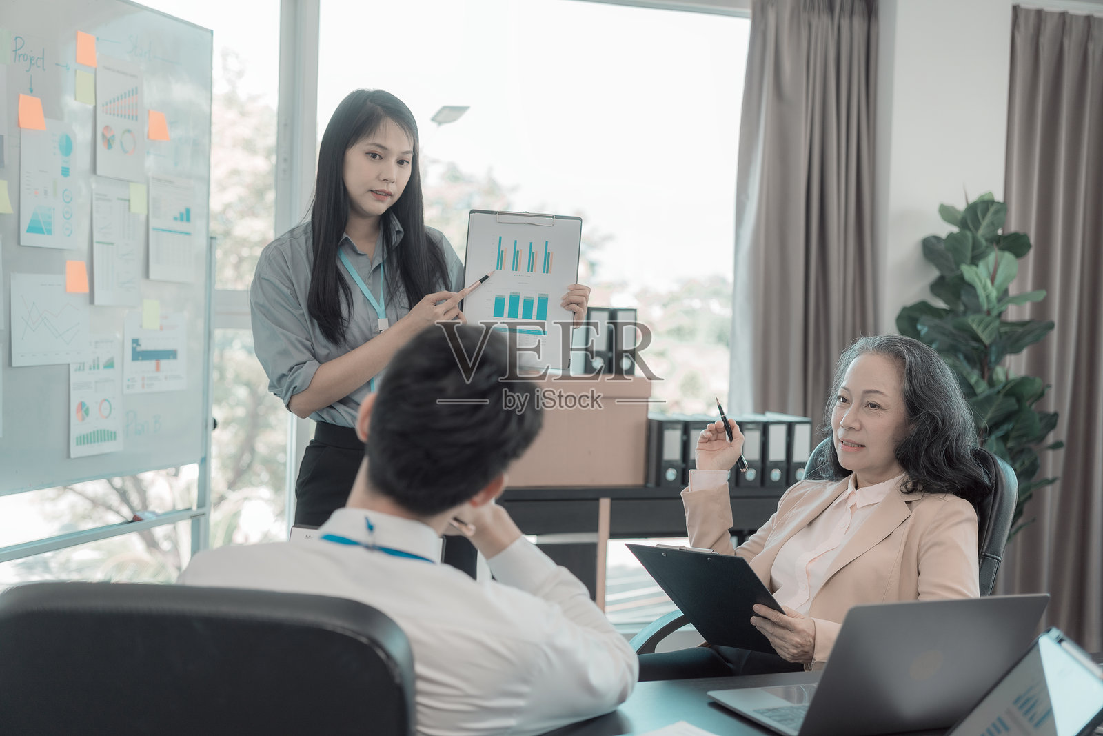 一群商务人士正在办公室里讨论图表，展示同事们在办公桌前协作工作的成果，并讨论文件。照片摄影图片