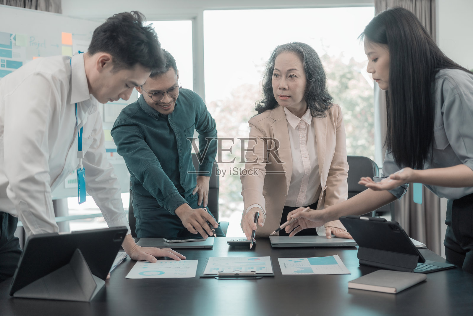 一群商务人士正在讨论展示团队合作成果的图表和图形，同事们在办公室的办公桌旁一起工作并讨论文件。照片摄影图片