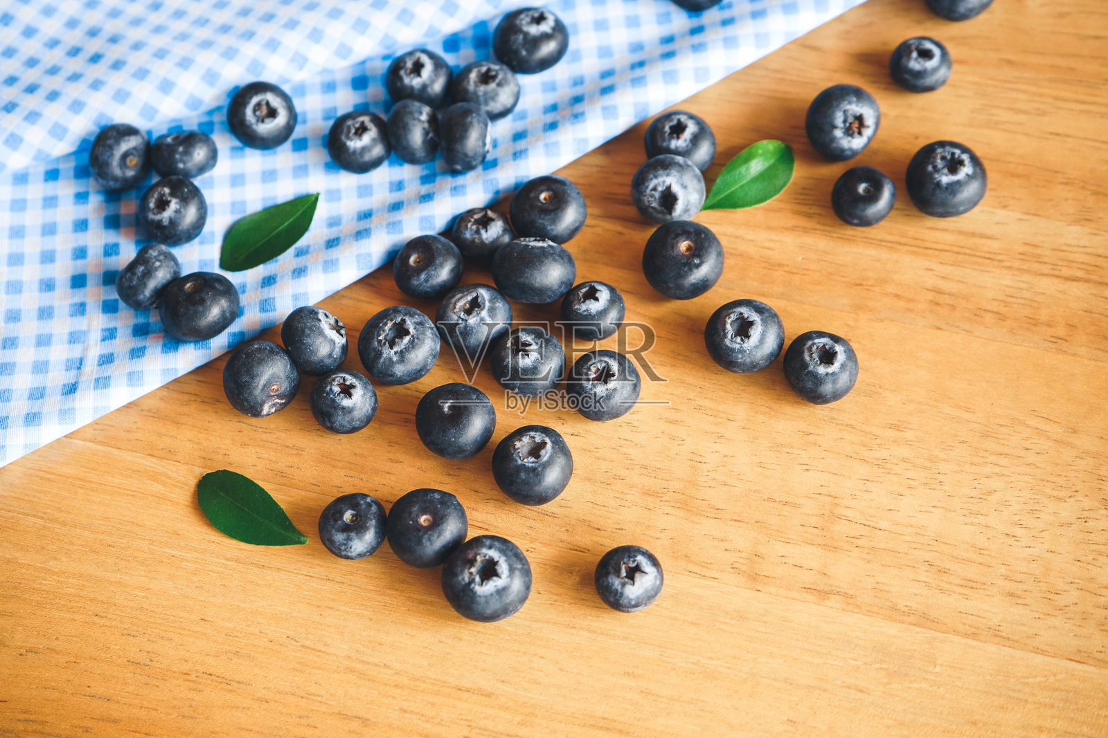 木桌上的新鲜蓝莓和蓝色桌布照片摄影图片