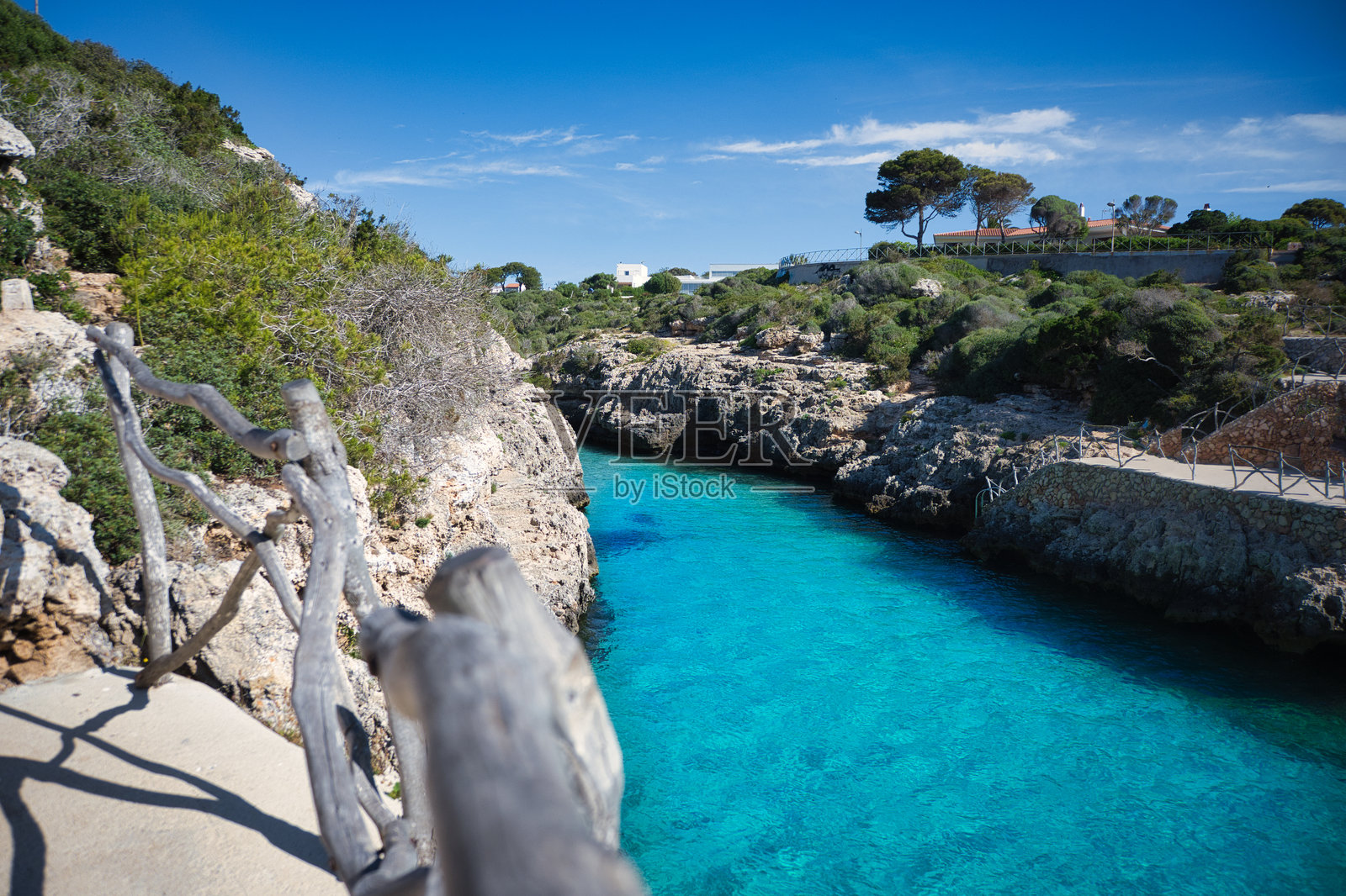 木制栏杆俯瞰着梅诺卡岛卡拉恩布鲁特 (Cala en Brut) 的水域照片摄影图片