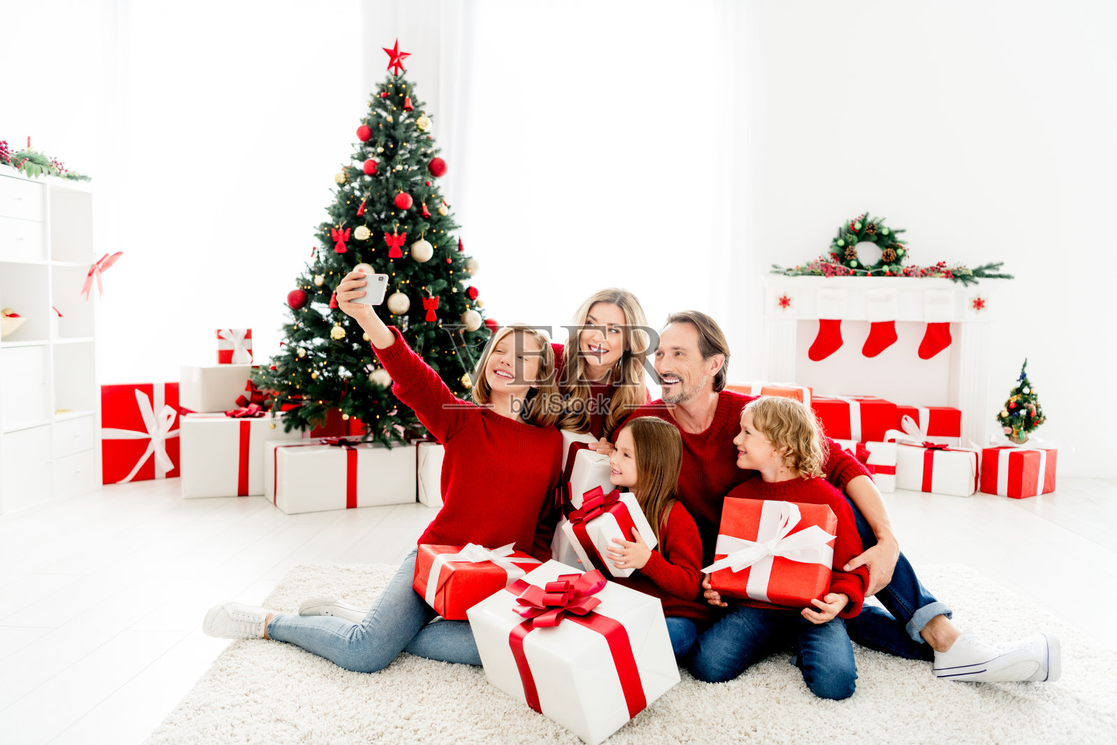 一家人温馨舒适地在家中庆祝圣诞节，有圣诞树、礼物，脸上洋溢着笑容。照片摄影图片