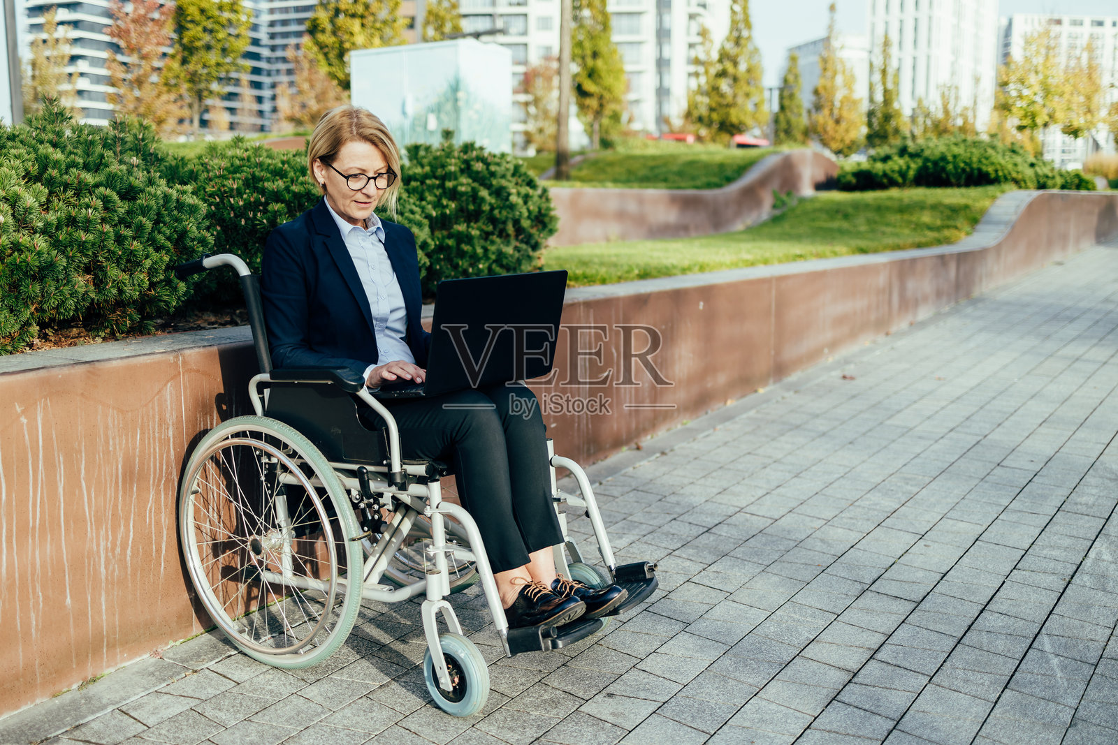 坐在轮椅上的女商人正在户外使用笔记本电脑工作照片摄影图片