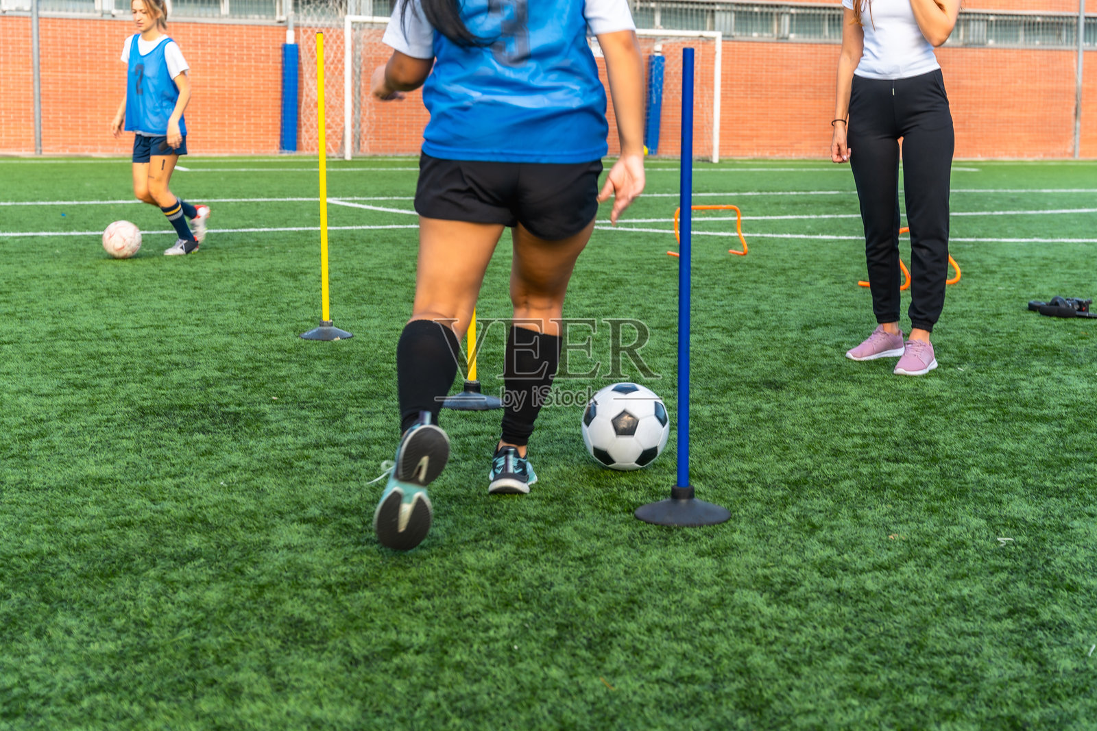 女子在人造草坪球场上训练踢足球照片摄影图片