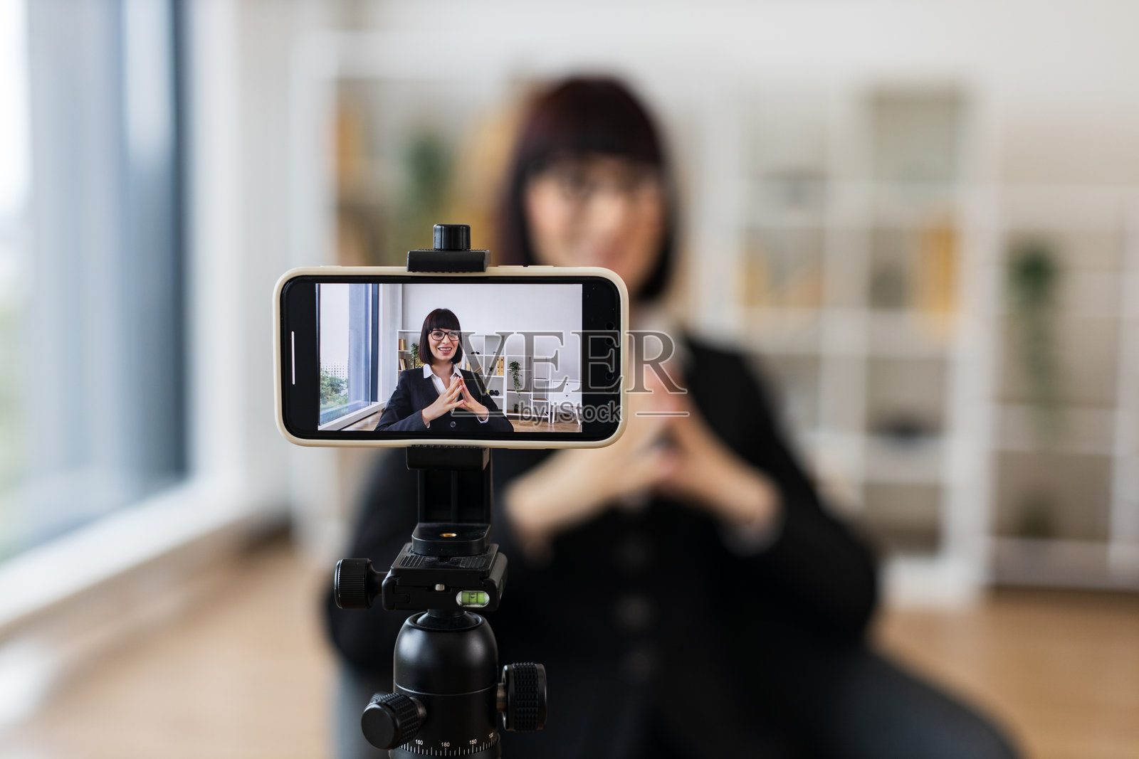 一位白人女性在现代办公室用智能手机录制商业vlog照片摄影图片